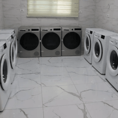 غرفة الغسيل الحديثة في سكن قصر الصفوة للطالبات قرب الجامعة الأردنية في عمّان، مزودة بغسالات أوتوماتيكية ومجففات وحماصات ضمن بيئة آمنة ونظيفة توفر راحة الطالبات اليومية.