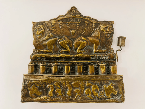 חנוכייה מברונזה עם תבליט אריות, כתובות עבריות ועיטורים מסורתיים