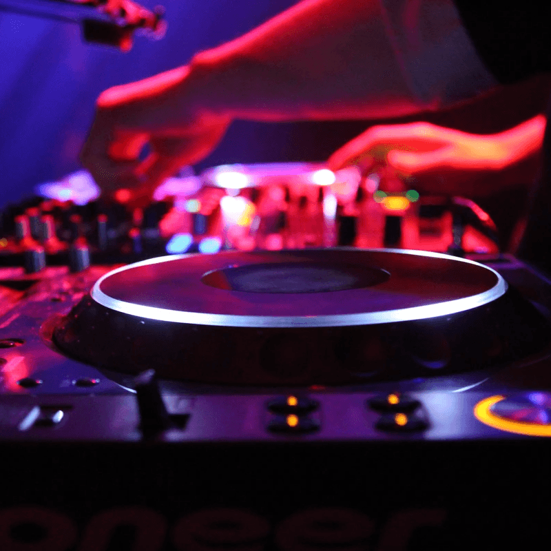 platines de dj avec mains en train de mixer en arrière plan 