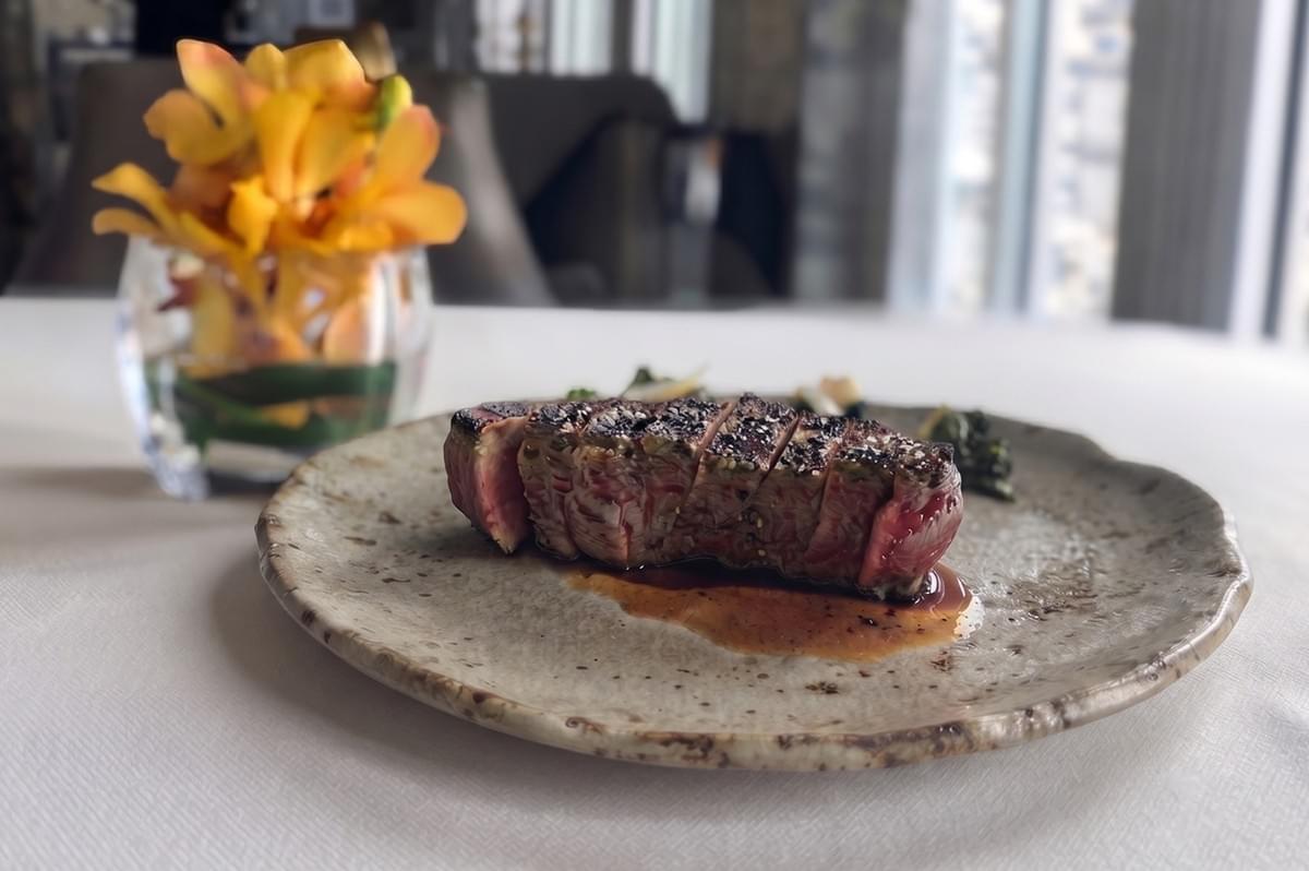 Sliced medium-rare steak served on a ceramic plate at Spago Dining Room.