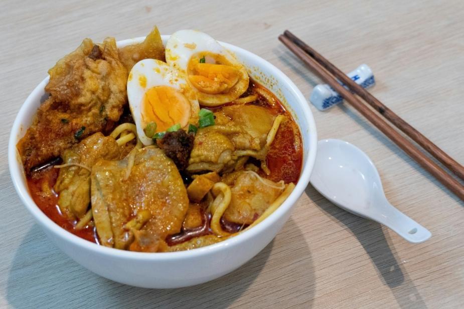 A photo of a laksa dish complete with its ingredients like noodles, to utensils like chopsticks.