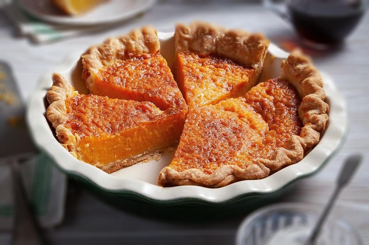 Homemade sweet potato pie sliced and served in a pie dish with a flaky golden crust.