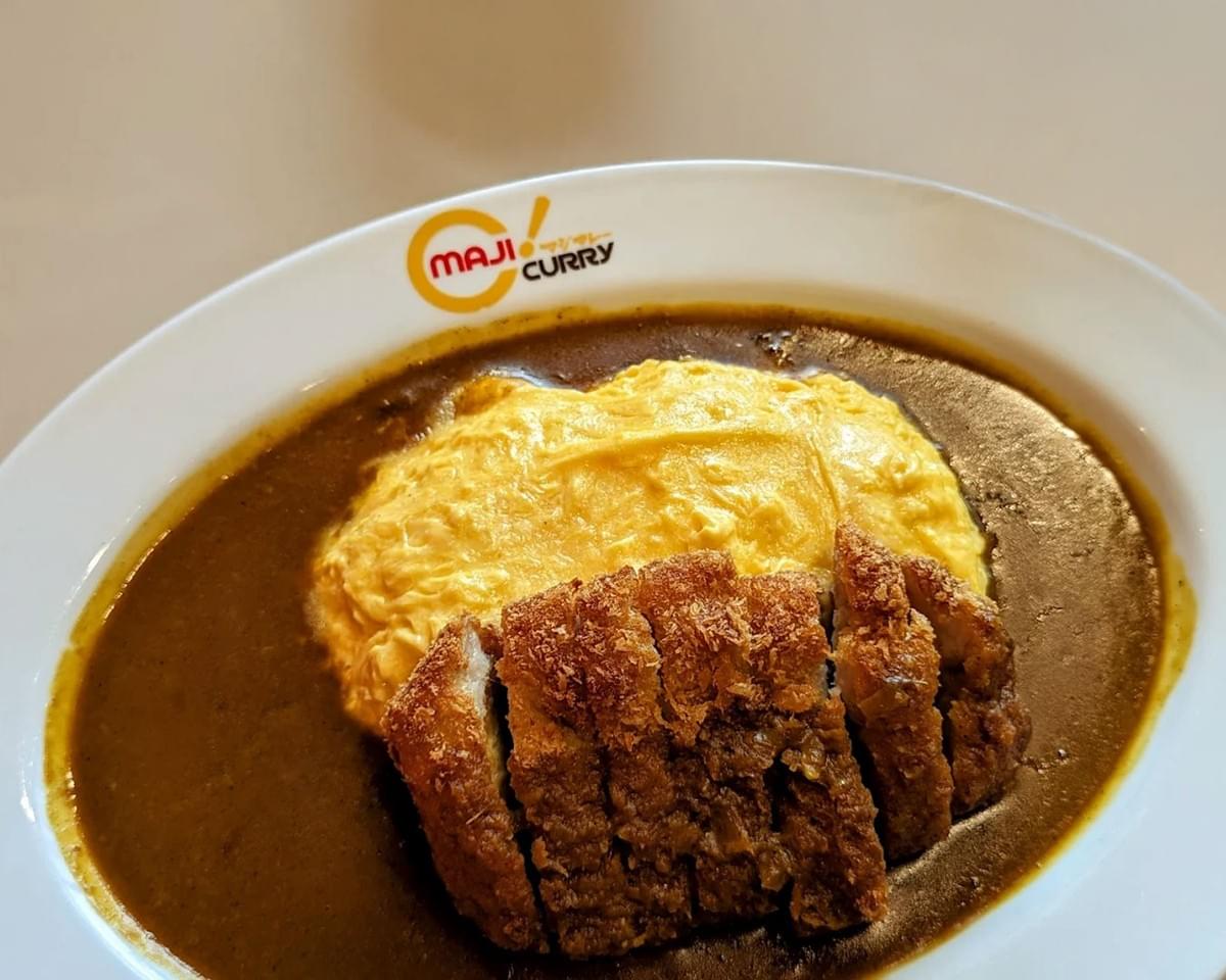 Maji Curry served in a modern Japanese style, with vibrant curry sauce, tender meat, and colourful vegetable accompaniments, plated elegantly.