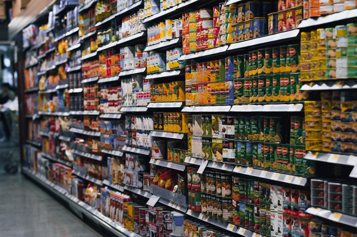 upermarket aisle filled with processed and canned foods highlighting decision fatigue and unhealthy food choices while living abroad, wide-angle perspective shot in grocery store