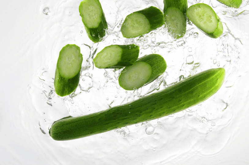 A top-down shot of a refreshing smashed cucumber salad, lightly garnished with sesame seeds and a drizzle of dressing in a dark ceramic dish.