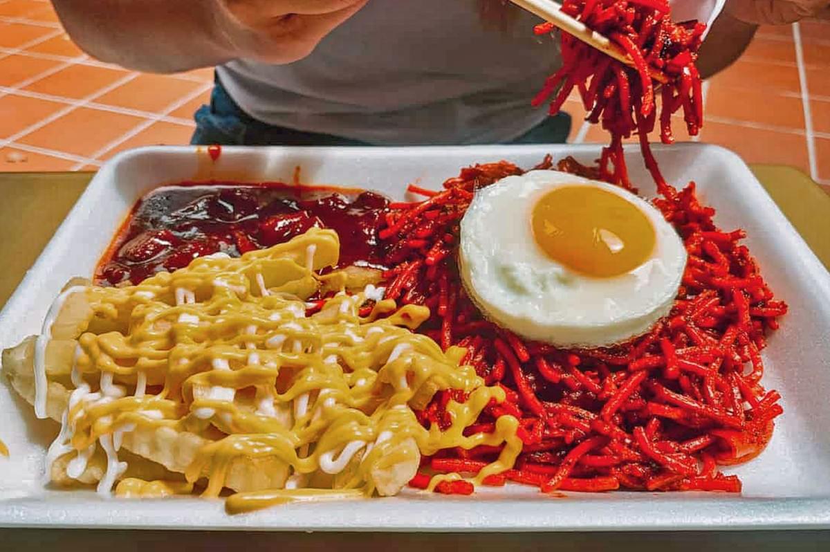 Person pov view eating pasta and fries with egg on a yellow table