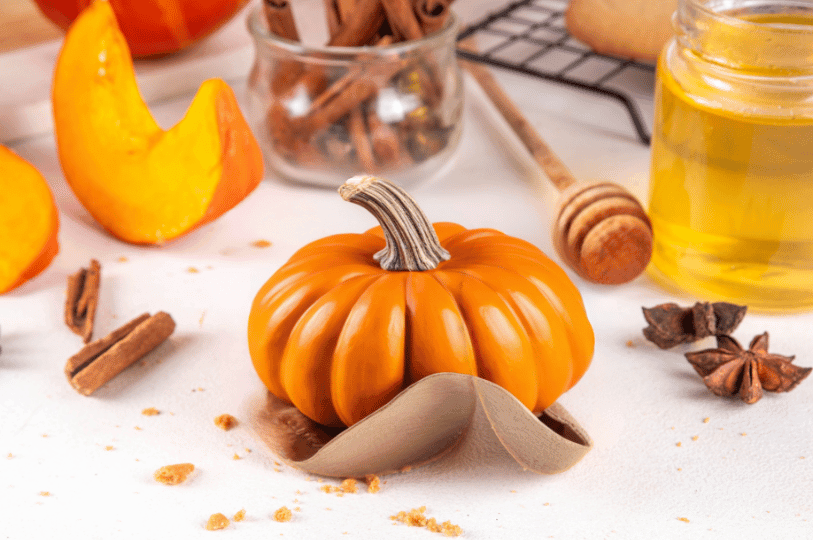 A small decorative pumpkin surrounded by cinnamon, honey, and baked crumbs—capturing the warm, spiced essence of autumn.