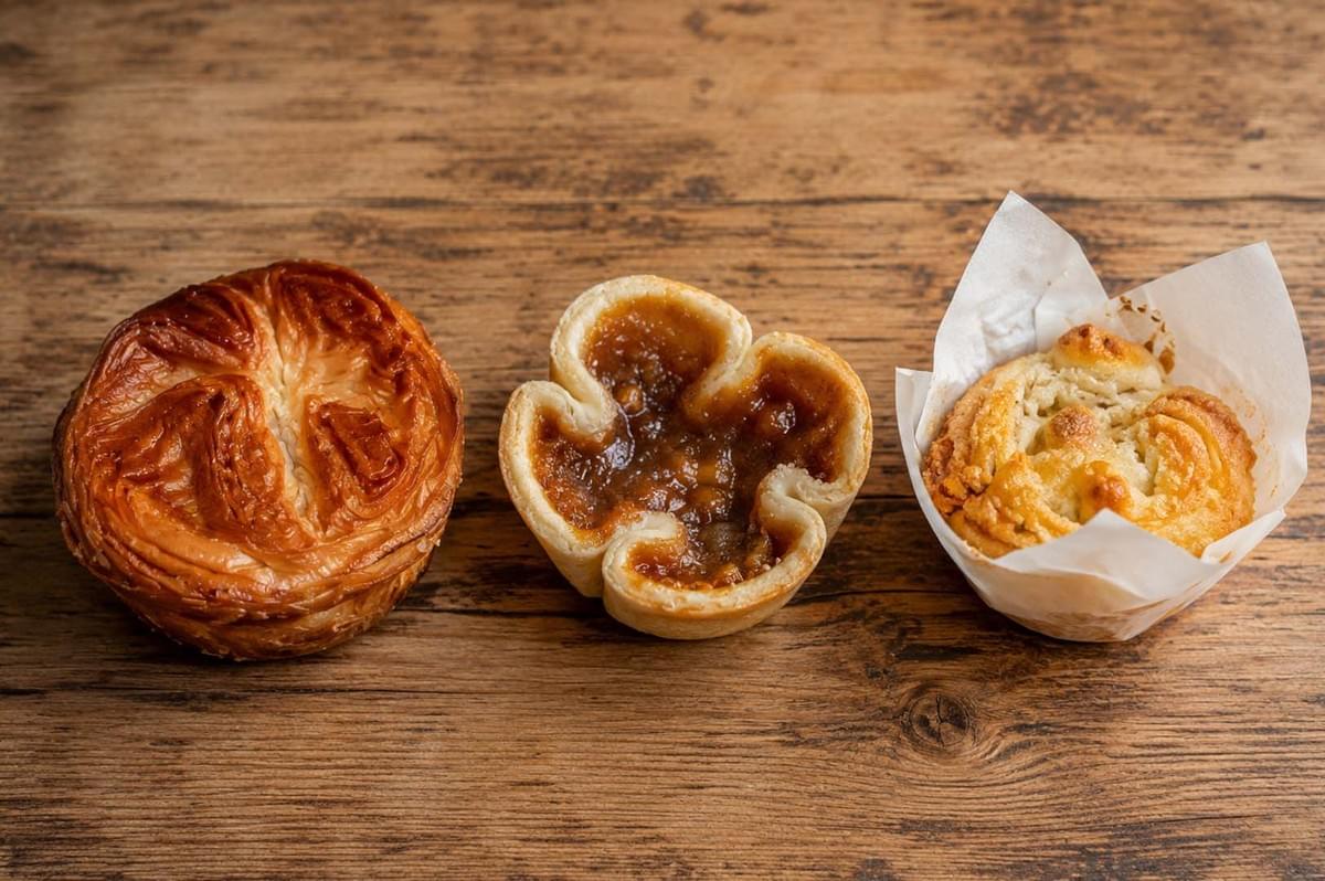 Three caramelized pastries lined up on a wooden table