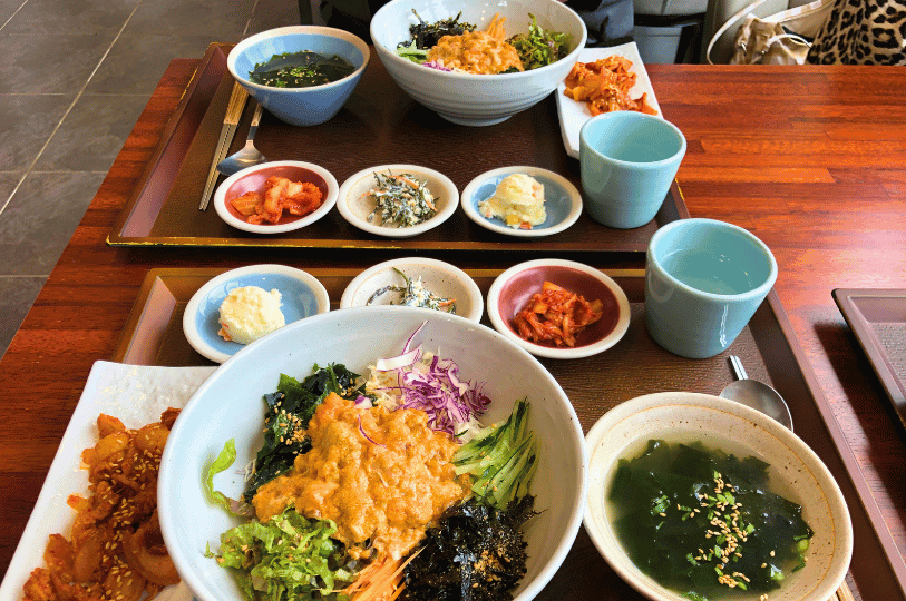 An open sea urchin shell revealing bright orange lobes of fresh uni, surrounded by whole, spiky black sea urchins.