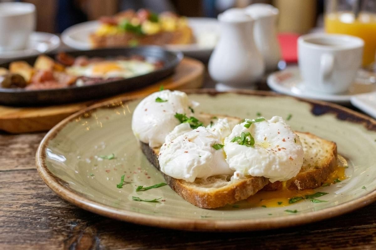 Poached eggs on toast with herbs served on rustic plate with breakfast spread