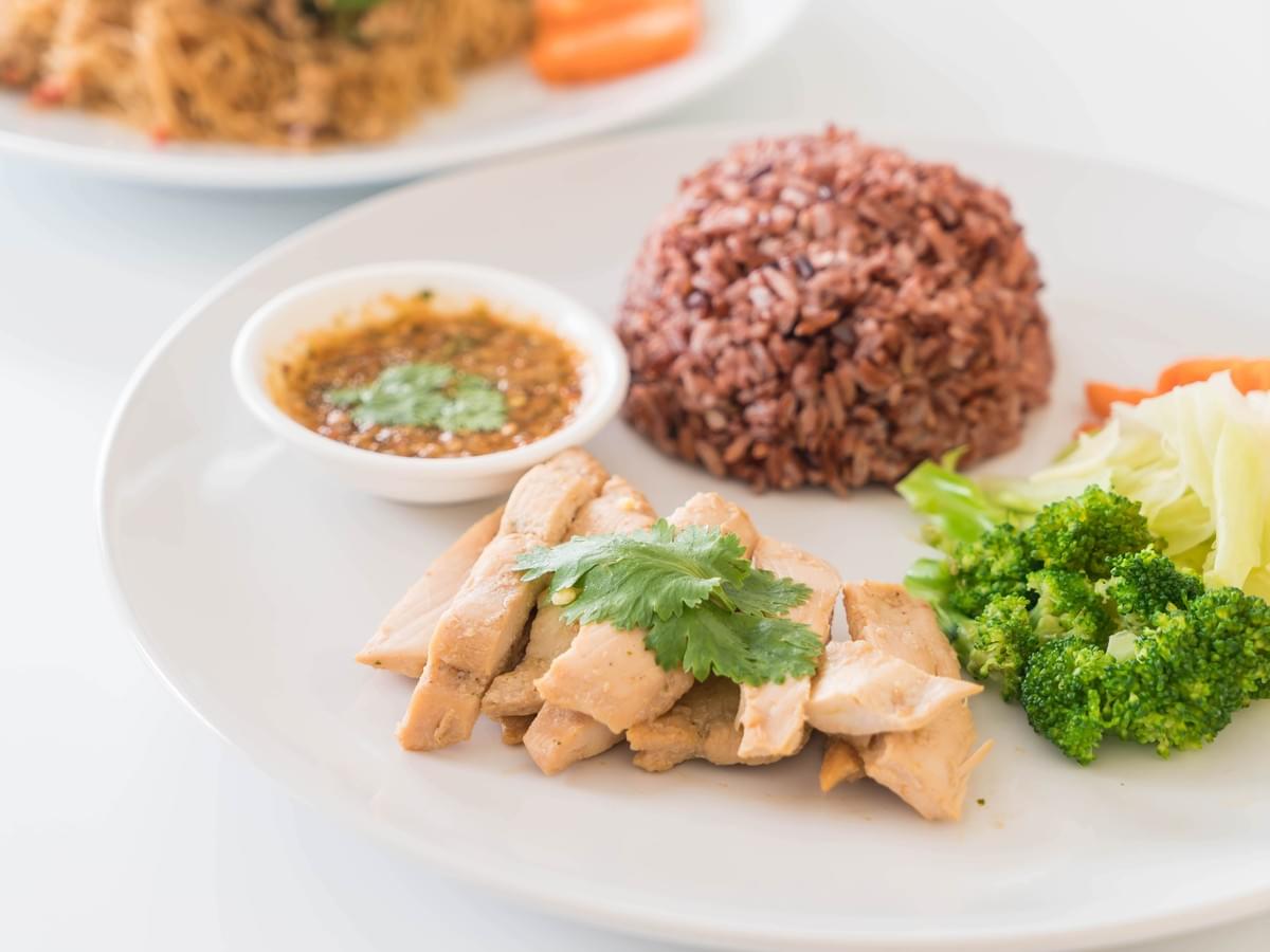 A vibrant photo of a chicken rice dish with herbs.