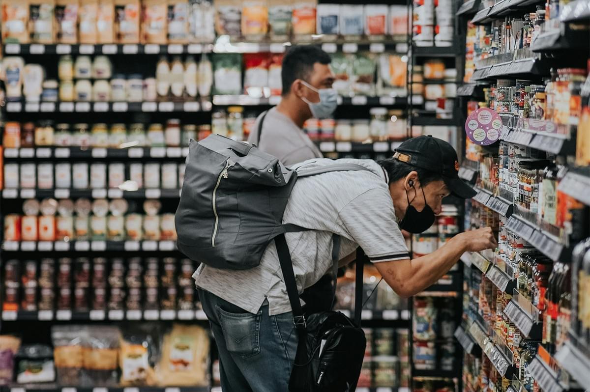 Person reading food labels and checking halal certification at a grocery store.