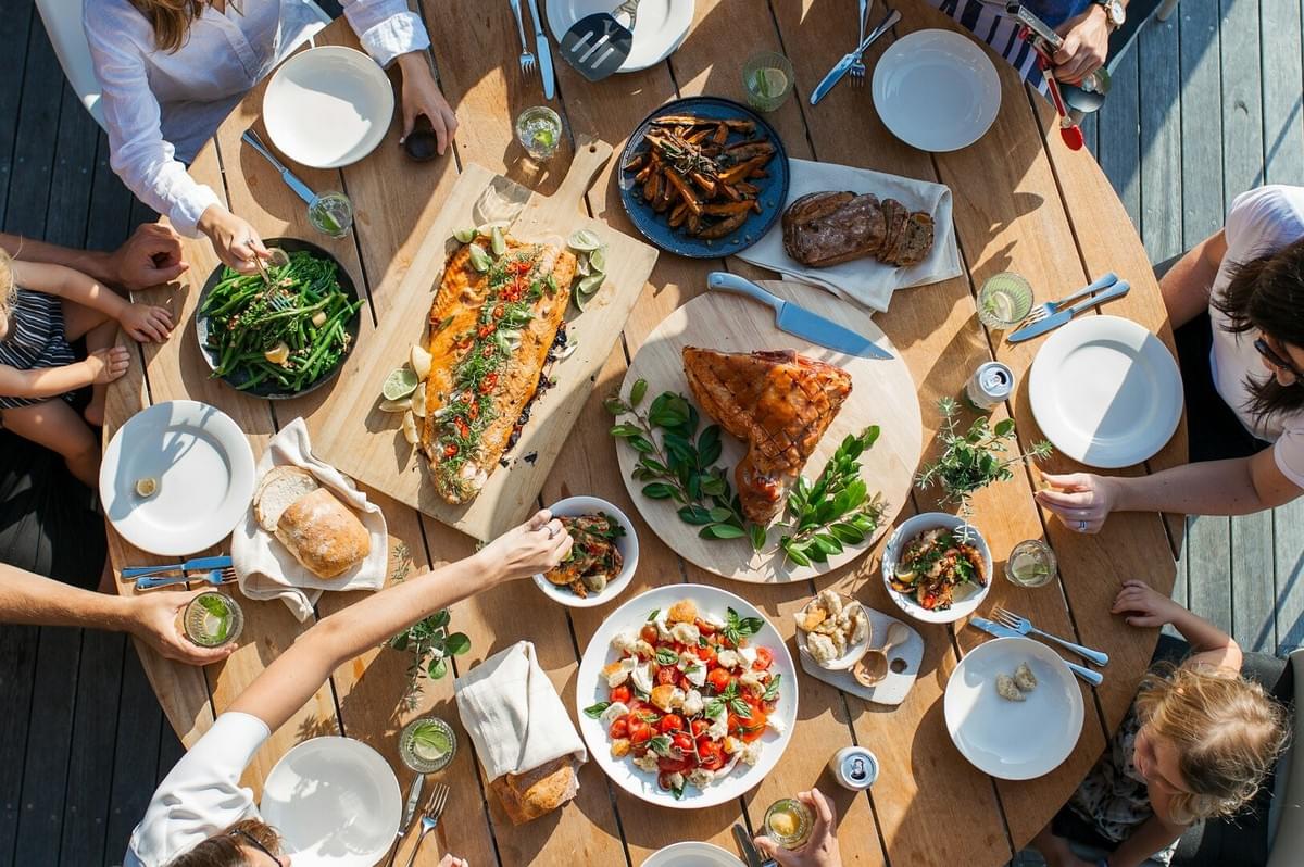 Friends and family seated at a table filled with food, celebrating the tradition of sharing meals throughout history.