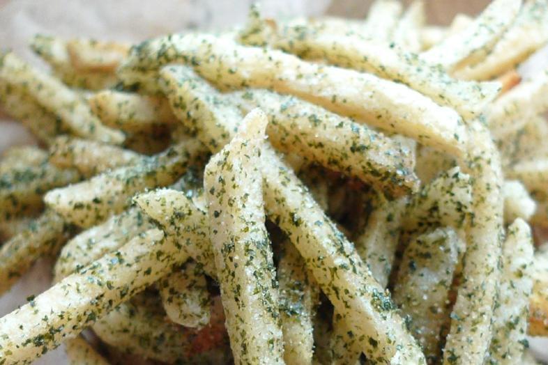 These are golden-brown french fries heavily coated in a fine, green seaweed seasoning. The fries appear crispy and are piled together, highlighting the savory flecks of nori and salt.