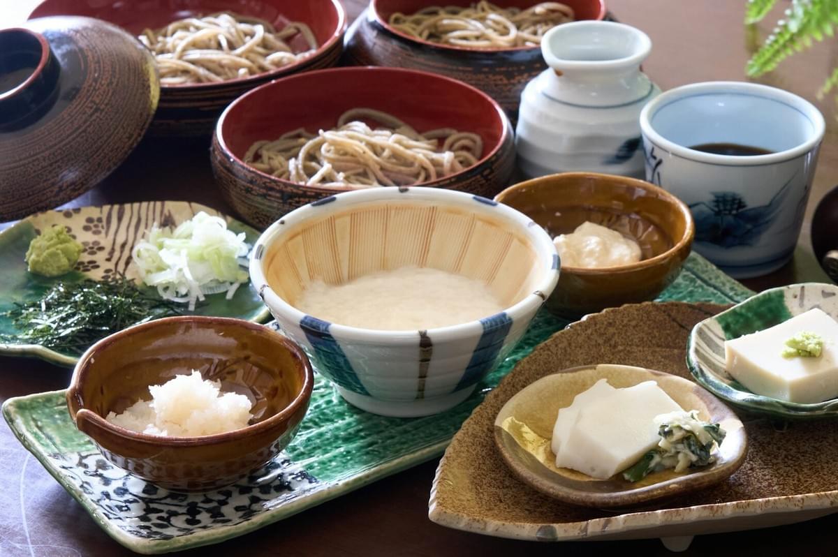 A table displaying various bowls of vegan Japanese dishes alongside bowls of rice, highlighting a vibrant meal spread.