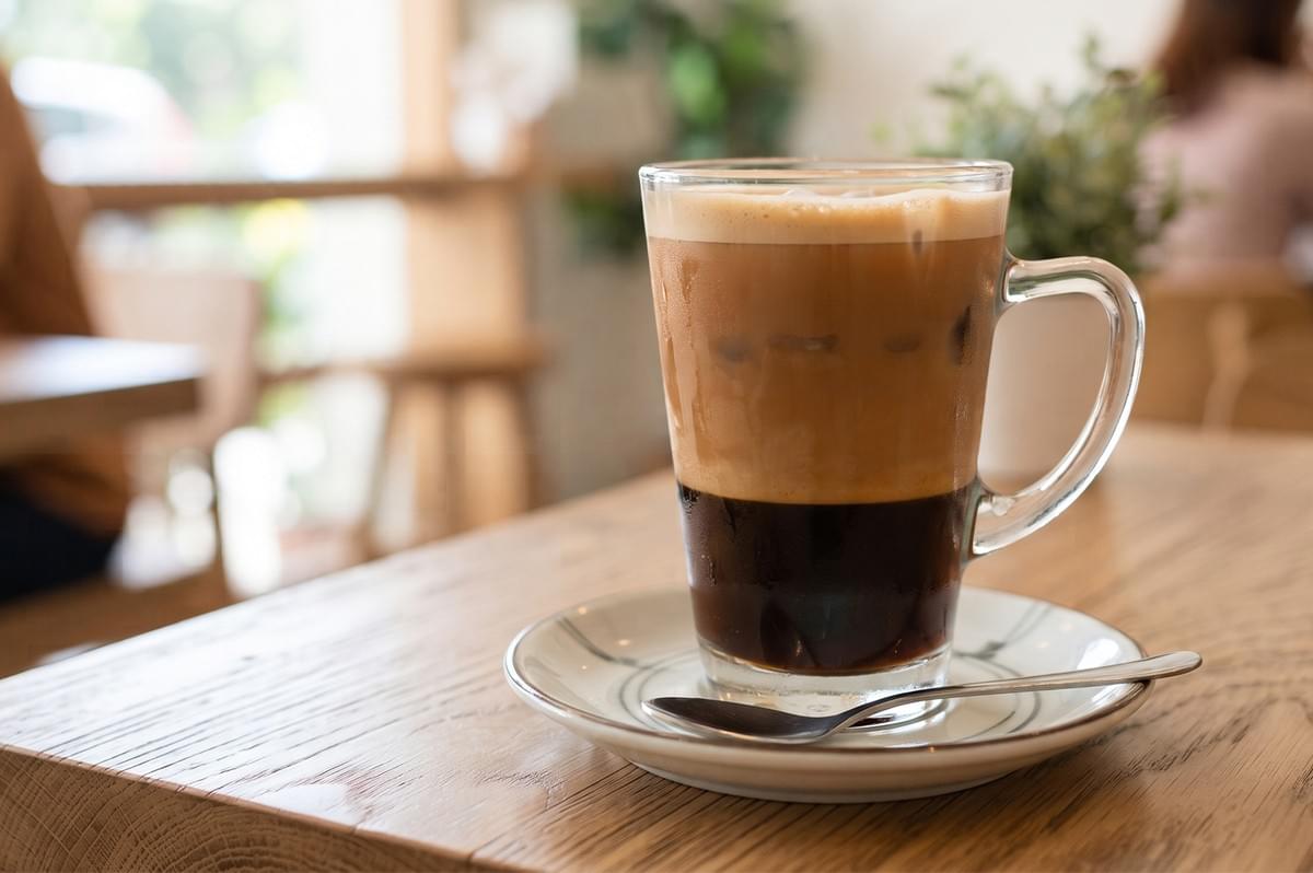 Glass of creamy Hong Kong style yuan yang coffee and tea served on a wooden table at a kopitiam.