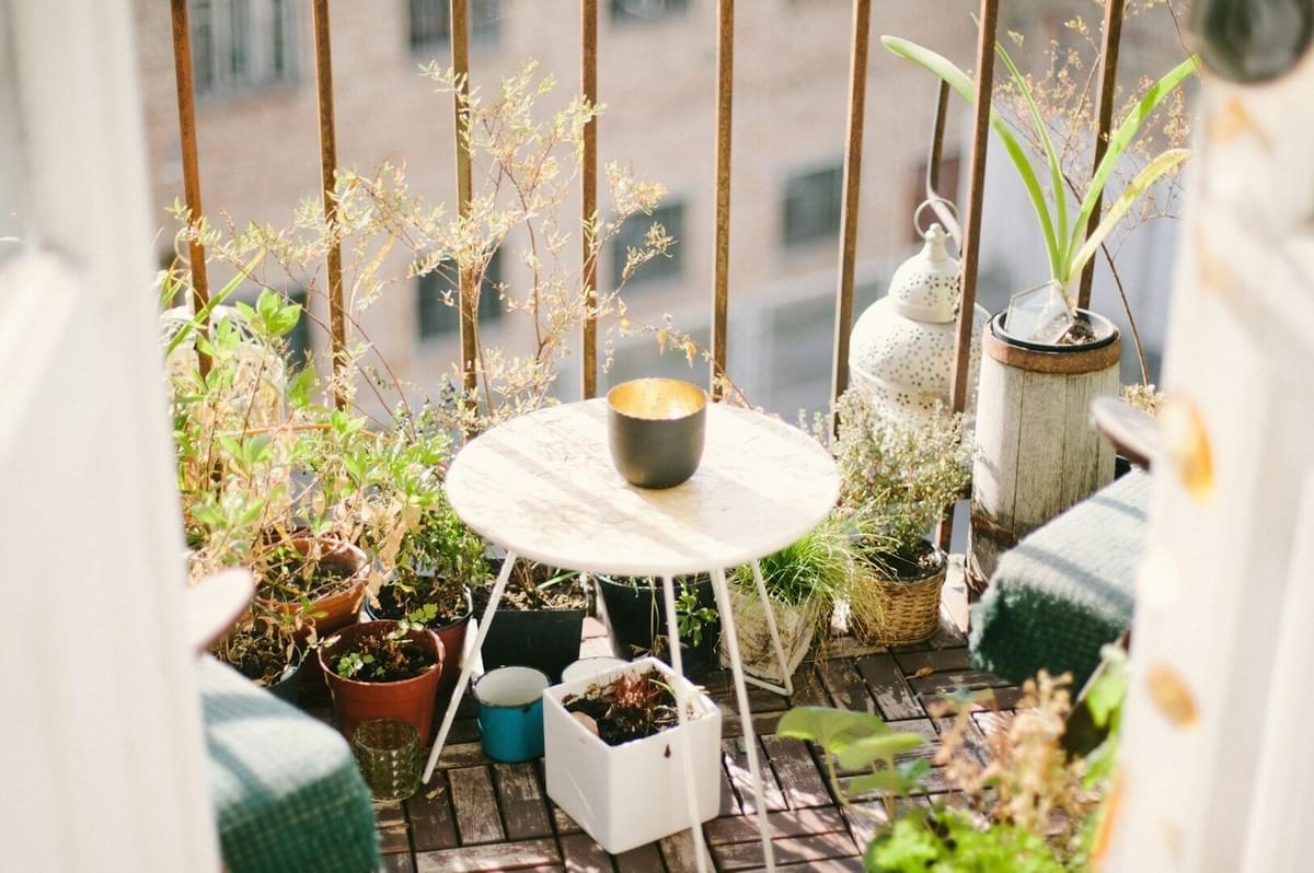 A balcony adorned with various plants and a table, offering a cozy setting for enjoying nature.