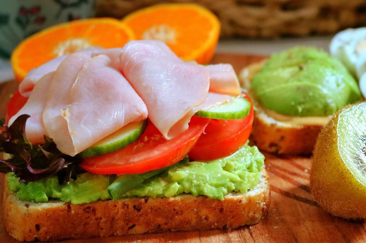 A plate featuring Danish open sandwiches alongside a selection of fresh fruit.