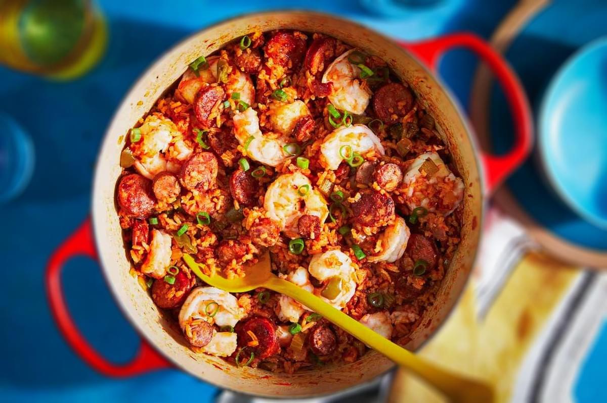 Louisiana jambalaya in a pot with shrimp, sausage, rice, and green onions.