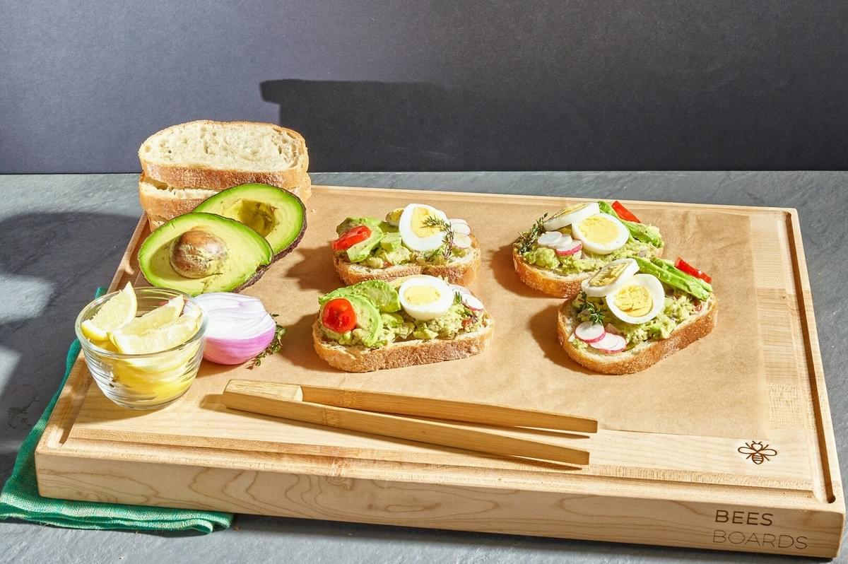 A wooden cutting board featuring an assortment of Nordic sandwiches alongside fresh bread.