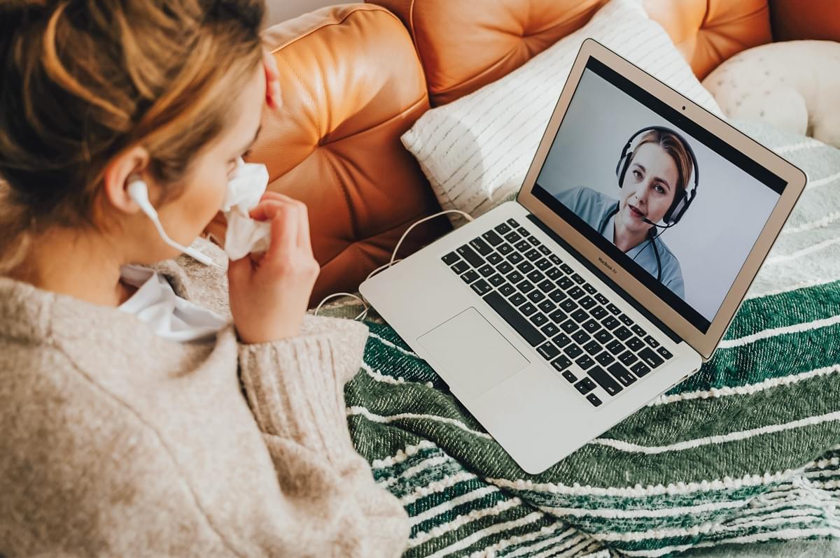 Overhead medium shot of person resting on couch while attending online therapy session via laptop, illustrating expat mental health support and coping strategies for emotional eating abroad