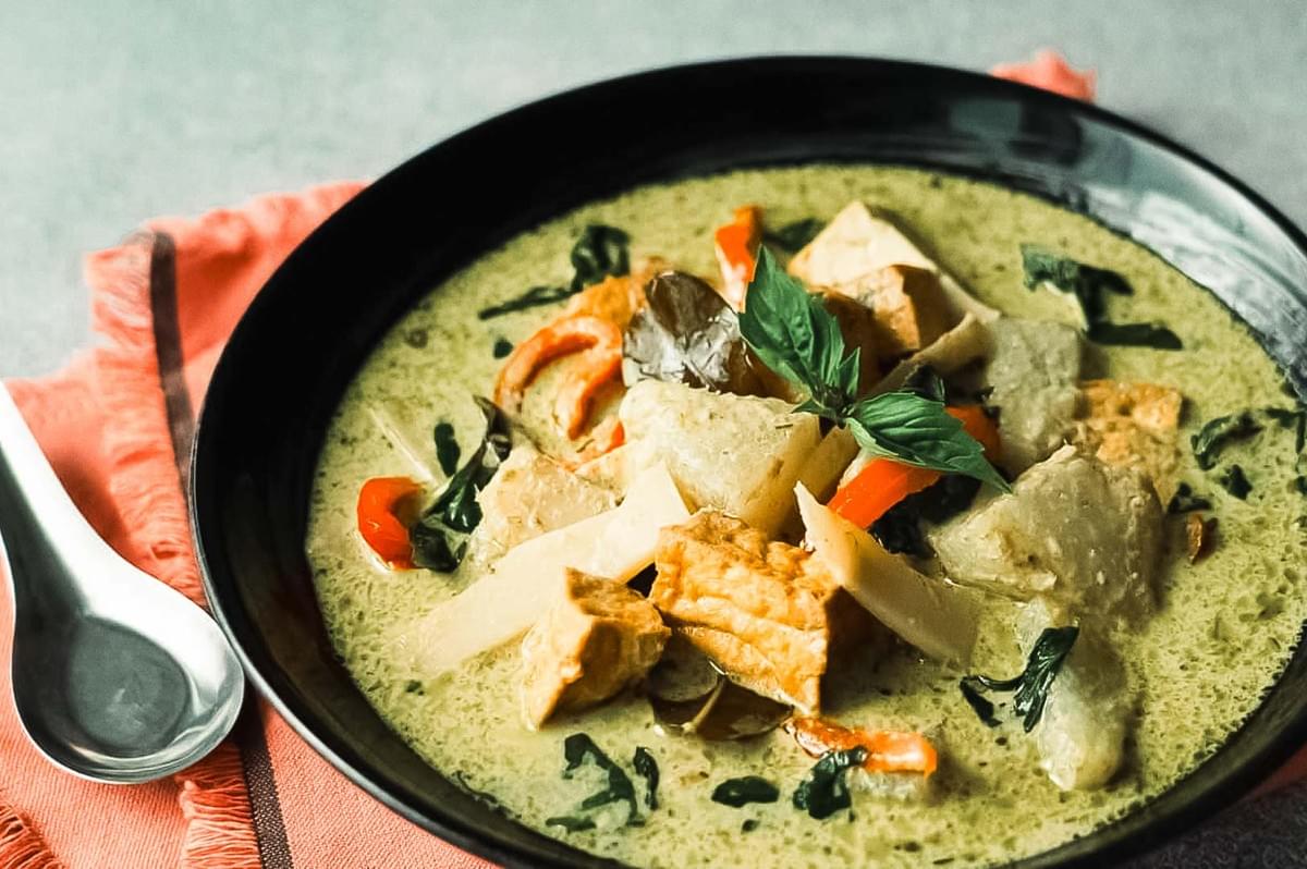 Filipino chicken adobo in skillet, glazed with soy-vinegar sauce and garnished with chopped green onions.