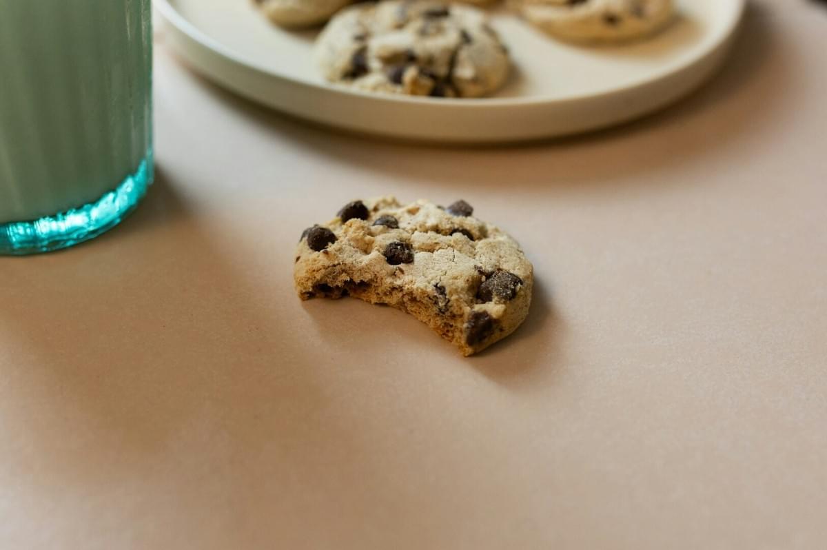 A plate of warm chocolate chip cookies beside a tall glass of milk, evoking feelings of culinary nostalgia.