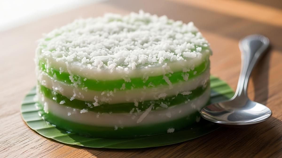 This round Southeast Asian dessert features vibrant alternating layers of translucent green and white topped with a dusting of shredded coconut flakes.
