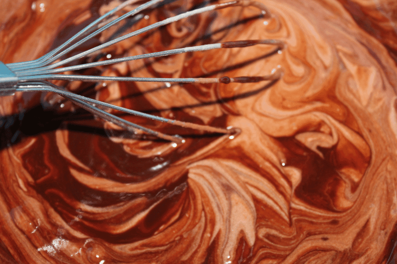 A close-up swirl of glossy chocolate batter being whisked—capturing the rich beginnings of brownie texture.