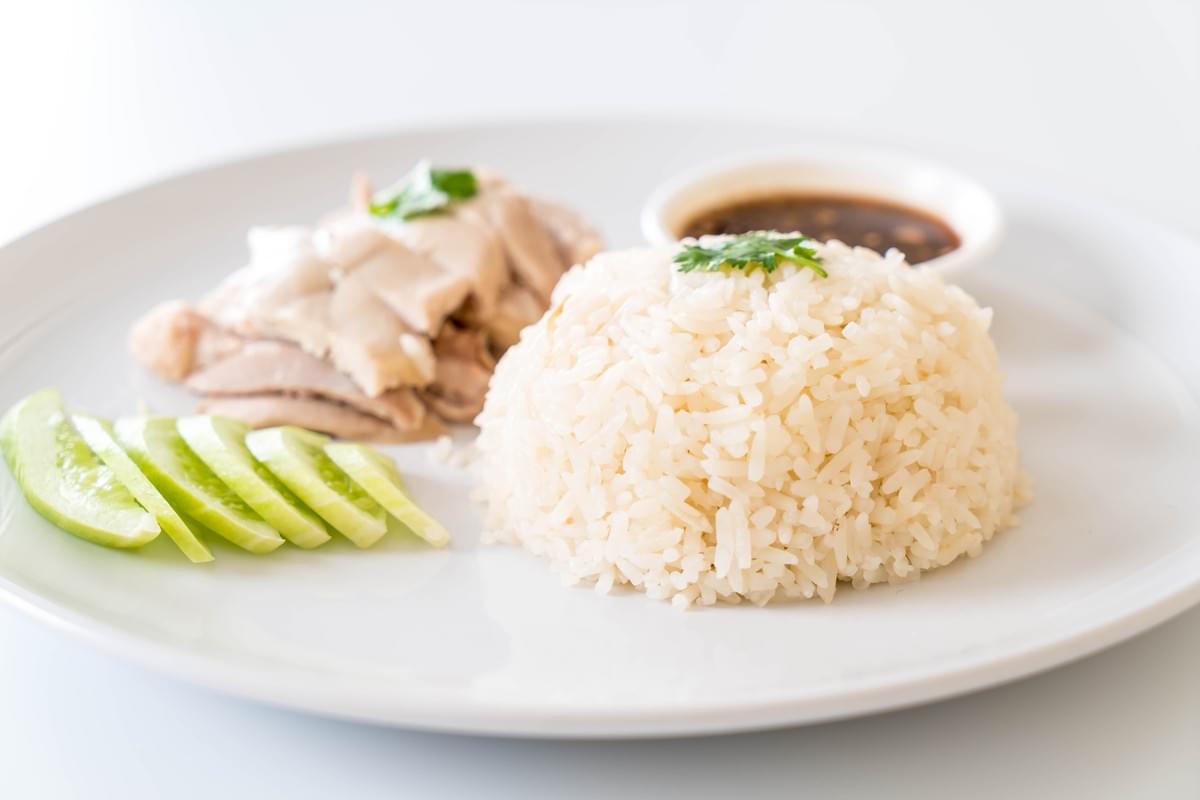 An image of an elegantly prepared Hainanese chicken rice on a white plate.