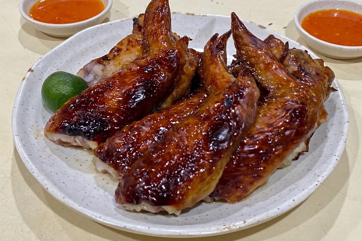Grilled BBQ chicken wings served with calamansi lime and chili dipping sauce at Bedok 85 Fengshan Market.