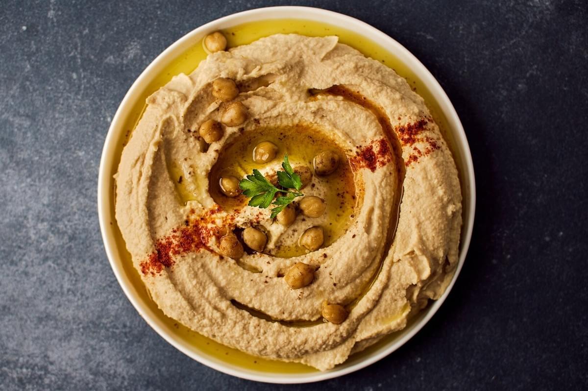 Hummus topped with chickpeas and parsley, served on a plate, representing an authentic hummus recipe.
