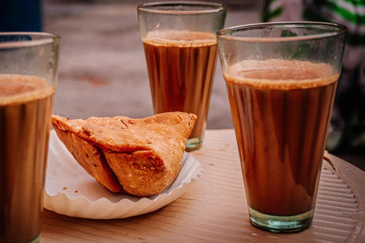 Three glasses of teh tarik and a pastry arranged on a table at a cafe in Singapore.