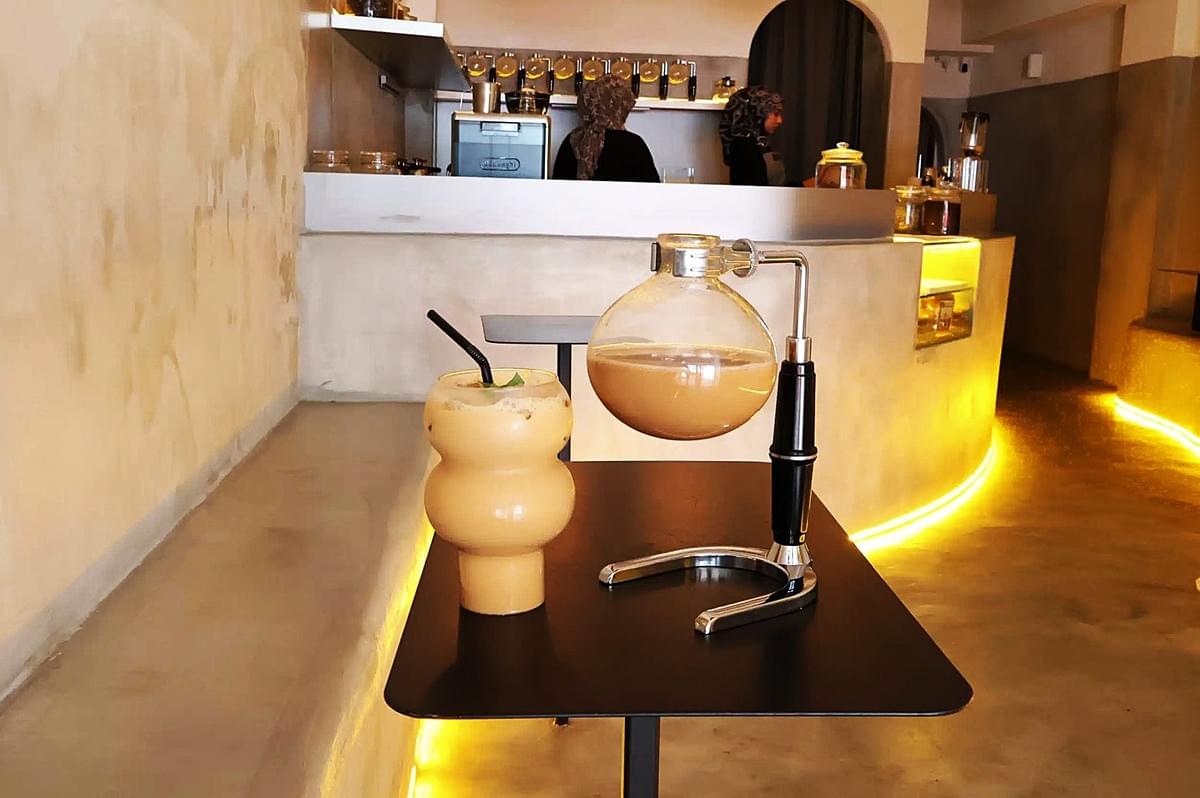 A coffee machine and a glass of Teh Tarik placed on a table, representing a traditional Singaporean beverage.