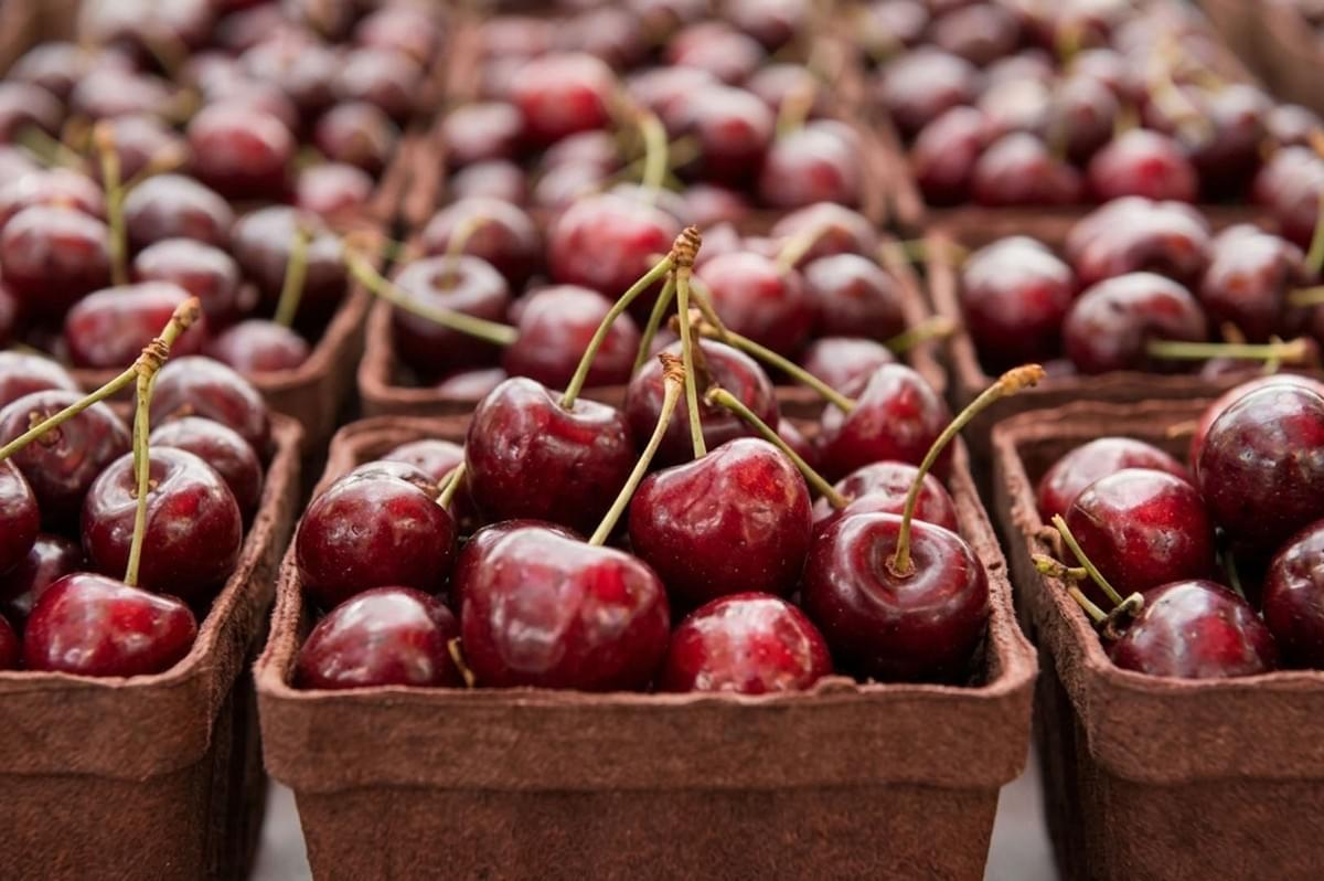 Baskets of fresh red cherries displayed at a farmers market or produce stand