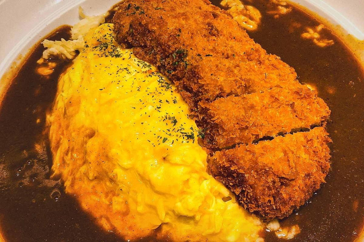 Japanese tonkatsu omelette curry featuring fluffy scrambled eggs, crispy breaded pork cutlet, and rich curry sauce.
