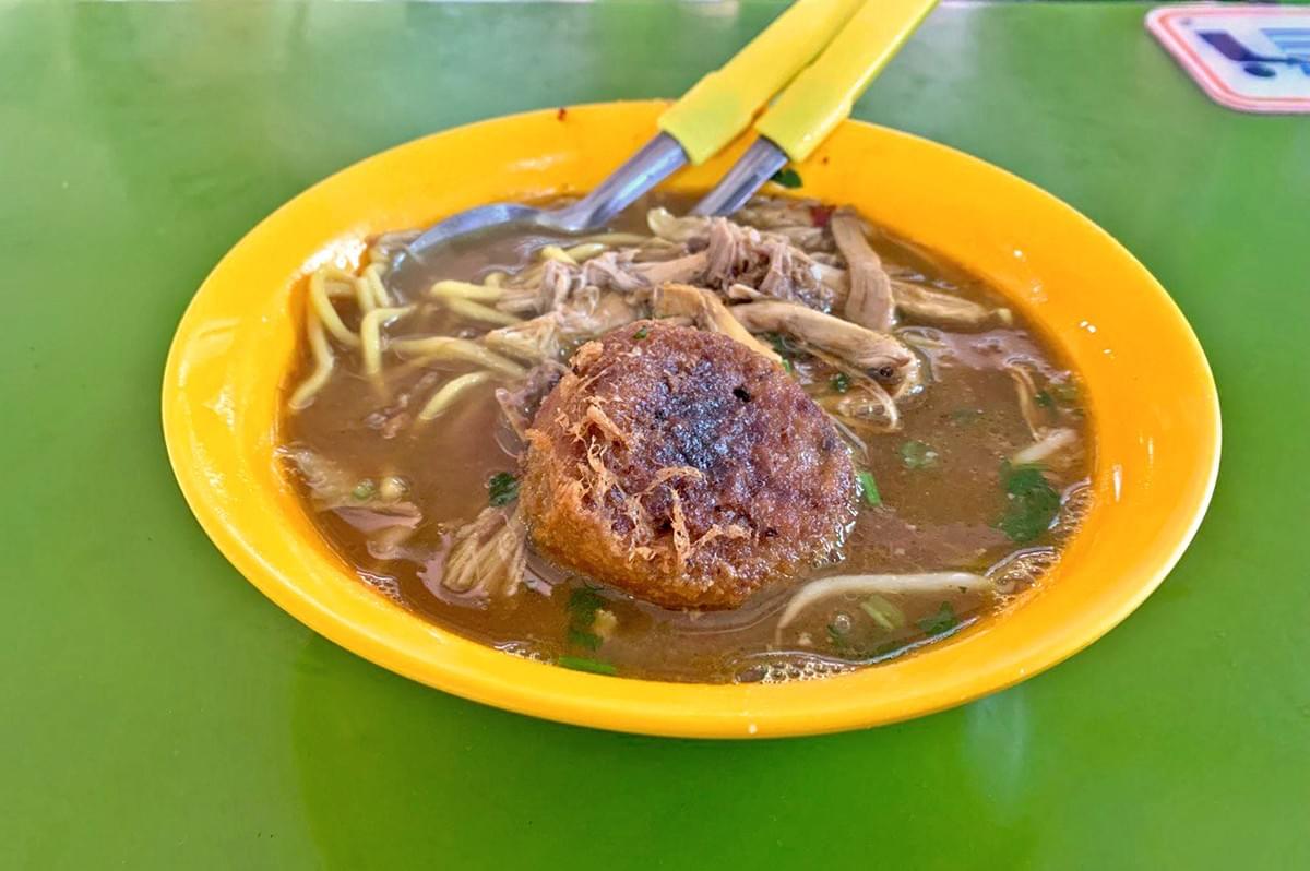 a bowl of a lemak dish placed on a green table