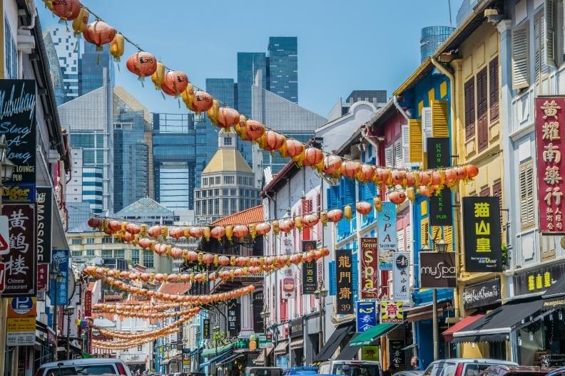 A photo of a Chinatown complex with its signature colorful design scheme with the iconic lantern having above the streets.