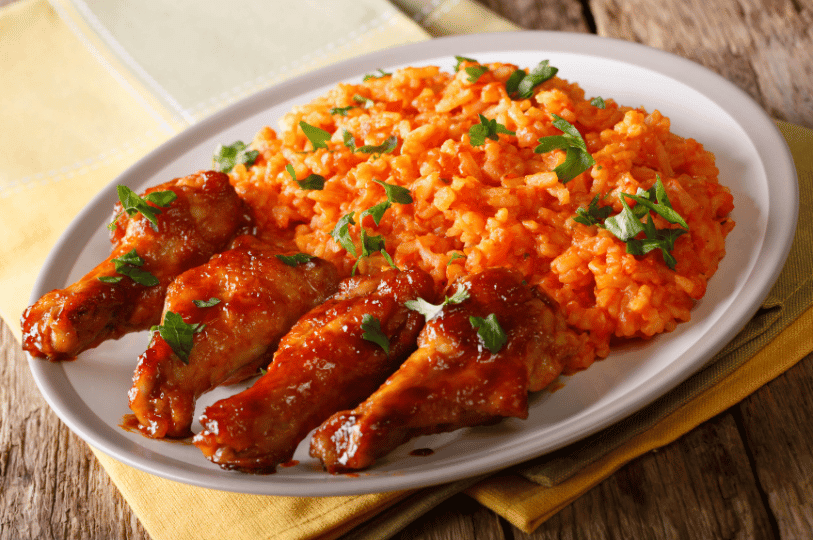 A top-down shot of a vibrant feast platter centered around Jollof rice, surrounded by colorful side dishes, perfectly grilled meats, and fresh vegetable garnishes.