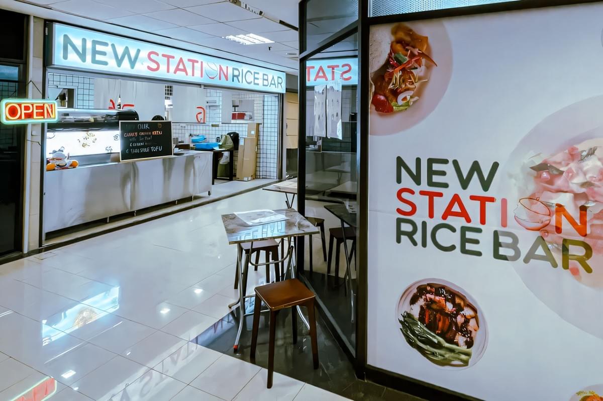 Interior view of New Station Rice Bar at Fortune Centre with bright signage, small dining tables, and a modern food counter in a clean mall setting.