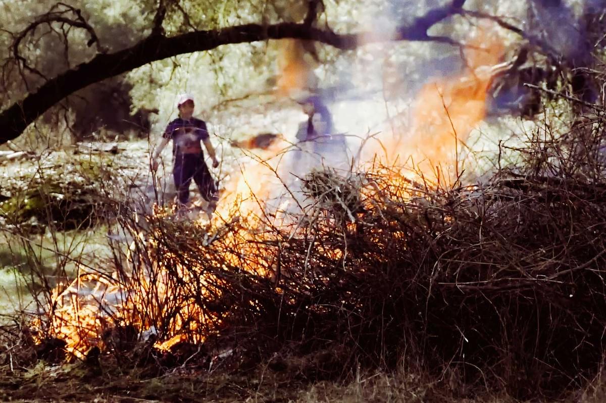 Brush burning in a field with smoke rising.