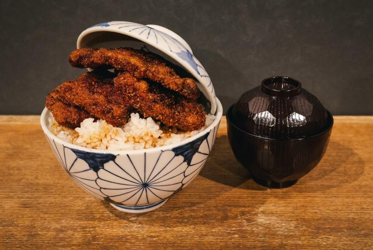 Japanese katsu don bowl piled high with crispy breaded pork cutlets alongside miso soup. 