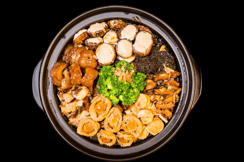 An overhead studio shot of a fully assembled Pen Cai on a black background, highlighting the symmetrical arrangement of luxury ingredients for Chinese New Year.