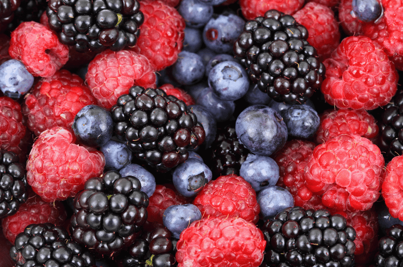 A macro shot of blackberries, raspberries, and blueberries, focusing on the intricate details and moisture on the fruit, perfect for discussing the importance of washing and drying berries before freezing.