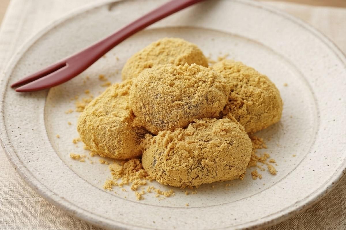 Mochi balls coated in golden kinako roasted soybean flour on ceramic plate with wooden fork