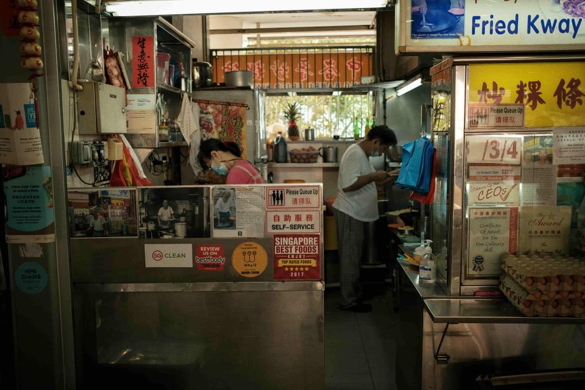 An image of two people working at a hawker stall during the day, preparing for the busy day ahead.