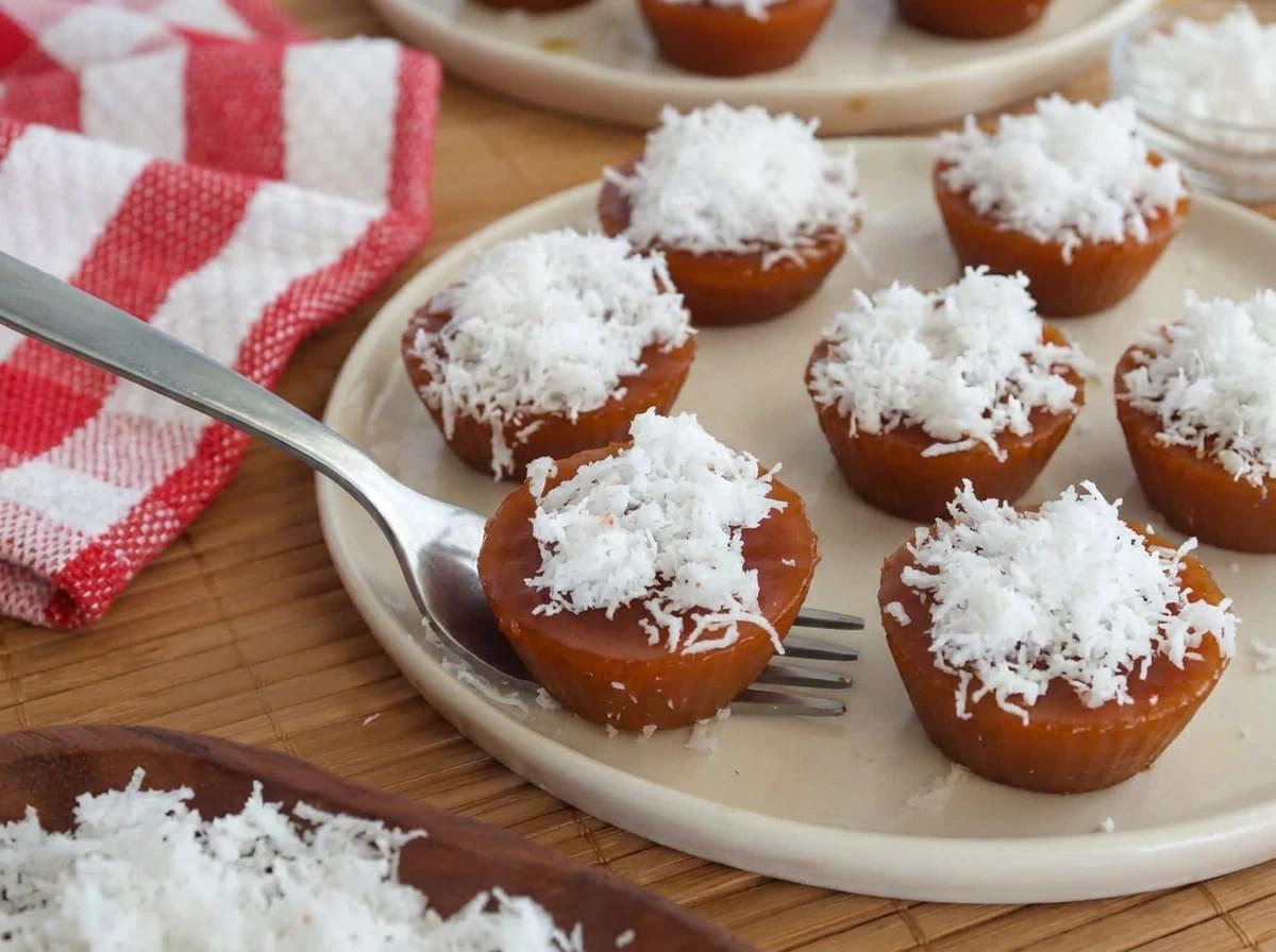 Bite-sized kutsinta topped with freshly grated coconut on a white serving plate.