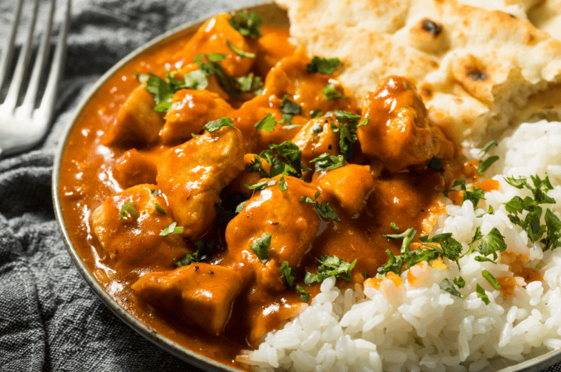 A vibrant plate of butter chicken in creamy tomato sauce, paired with fluffy rice and toasted naan—an inviting snapshot of Indian comfort food made simple.