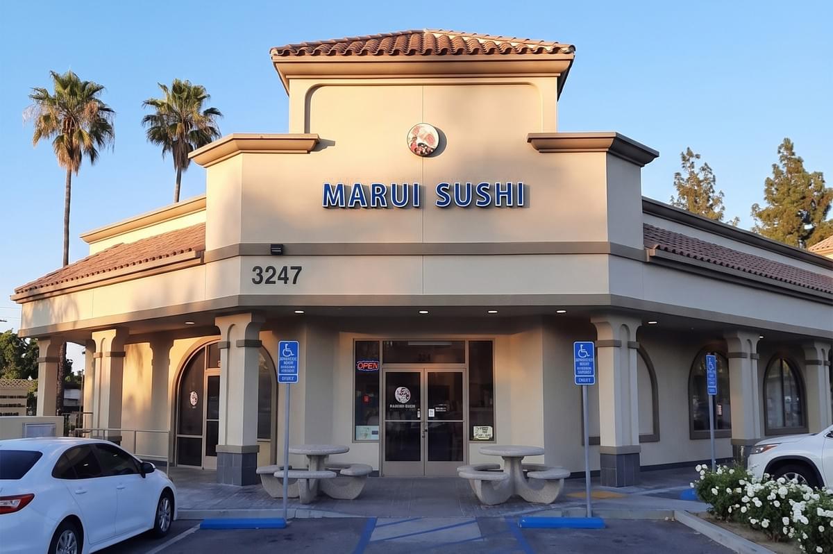 Marui Sushi restaurant storefront at 3247 with outdoor seating and parking
