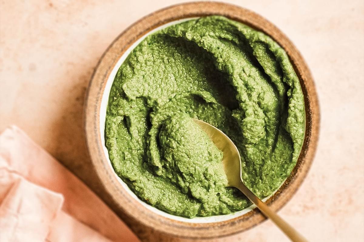 Thick homemade Thai green curry paste in a bowl with a spoon ready for cooking.